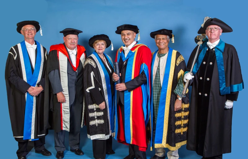 a bunch of men standing in gowns and wearing graduation regalities