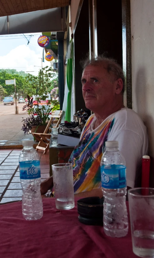 an older man sitting at a table with water bottles