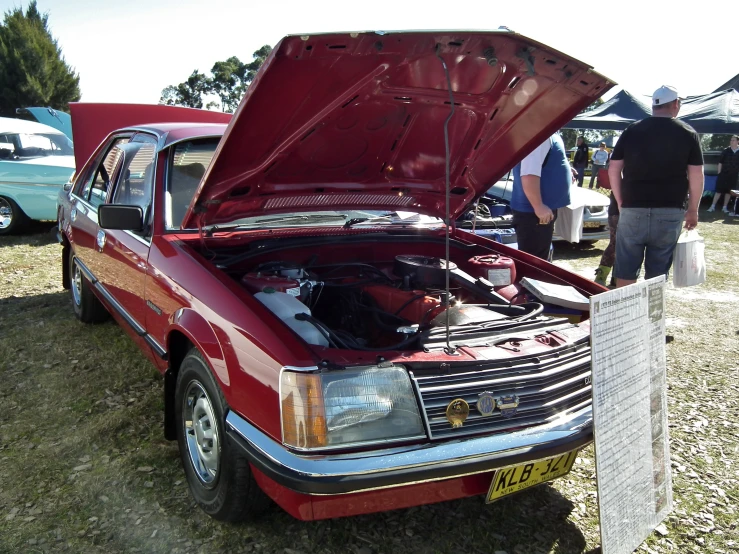 a car with its hood open next to people