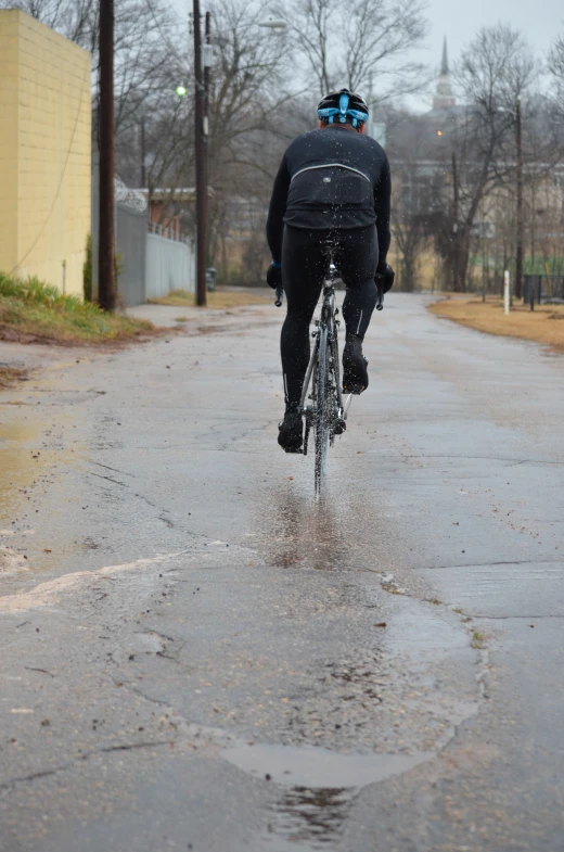 a bicyclist riding in the rain on a road