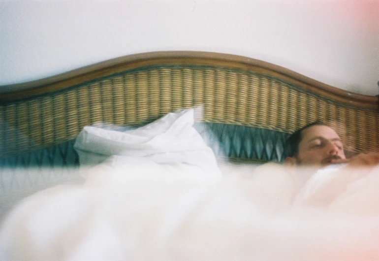 man sleeping on bed in front of wicker headboard