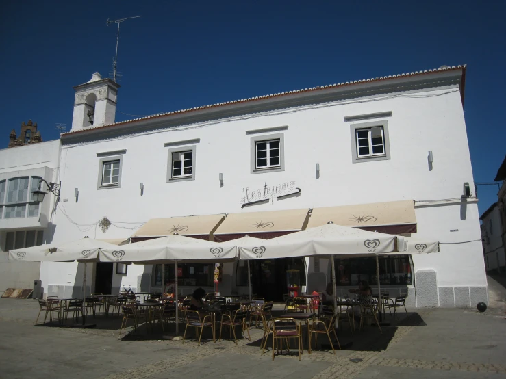 a white building with some tables and chairs outside