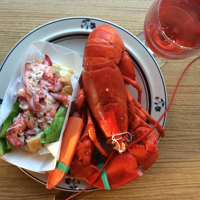 a close up of a plate of food with a lobster and fries on it