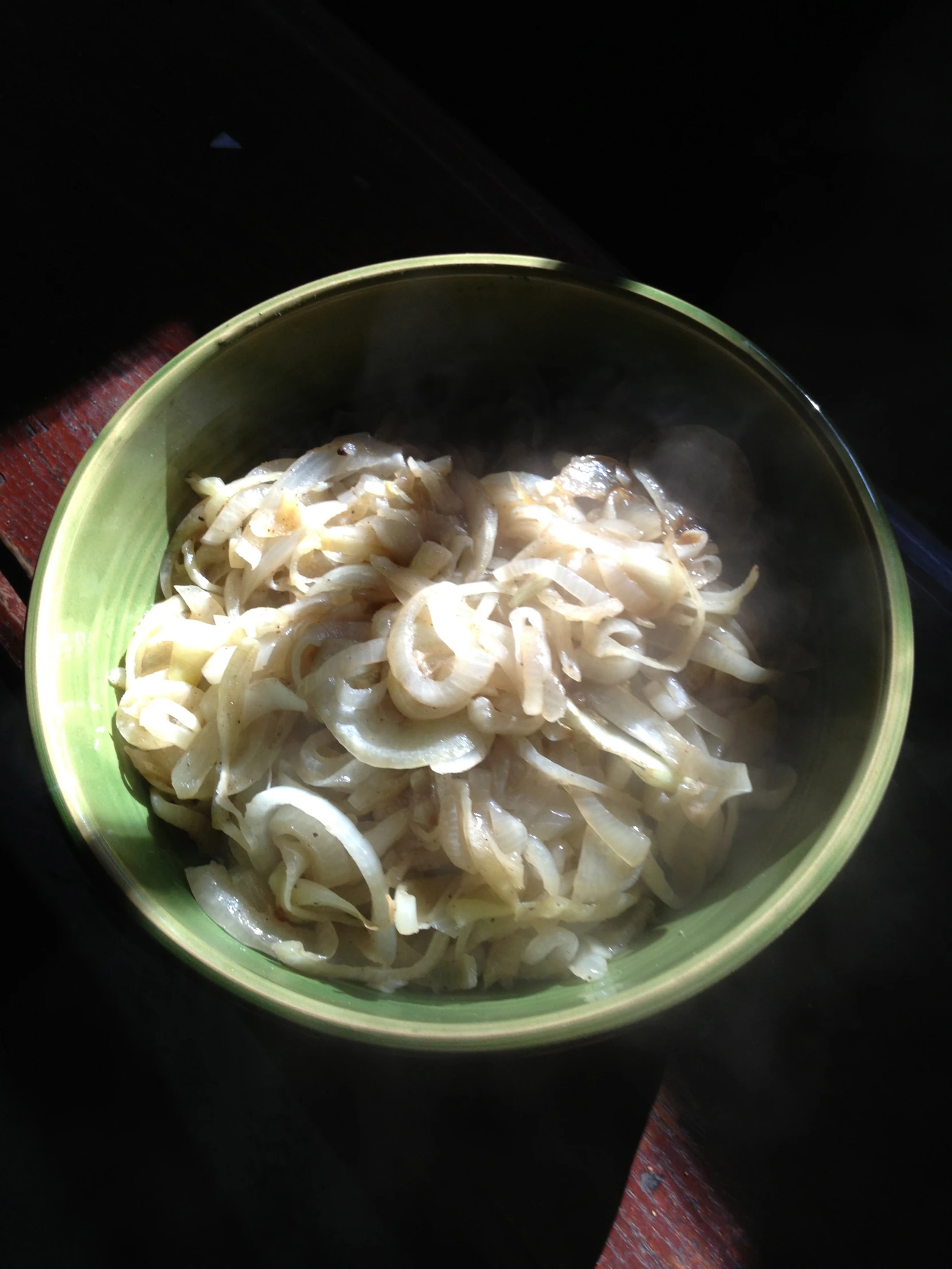 a green bowl filled with cooked noodles on top of a table