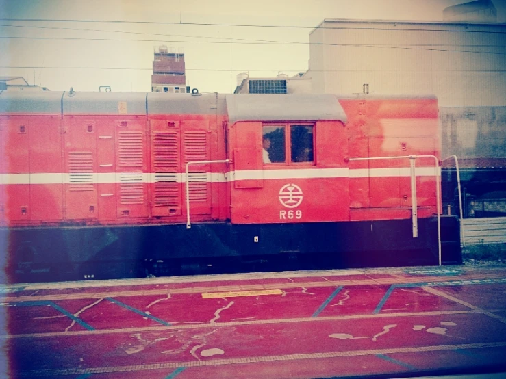 a red train sitting on top of an asphalt lot