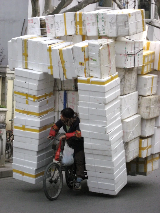 man riding a small bike loaded with large packages
