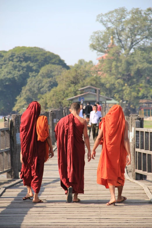 three monks are walking on a boardwalk