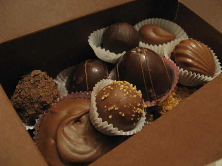 a box filled with chocolate covered donuts next to chocolate covered donuts