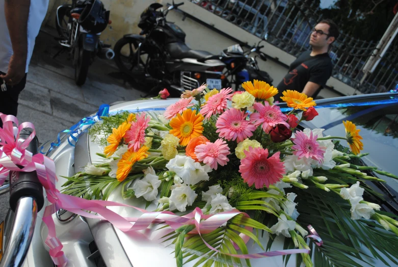 flowers on the hood of a motorcycle with a pink ribbon