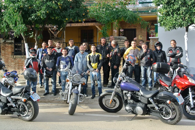 a group of men stand next to motorcycles in front of a building