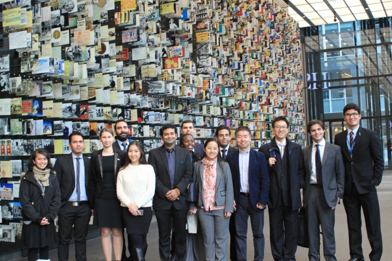 a group of business people pose for a po in front of a wall covered with magazines