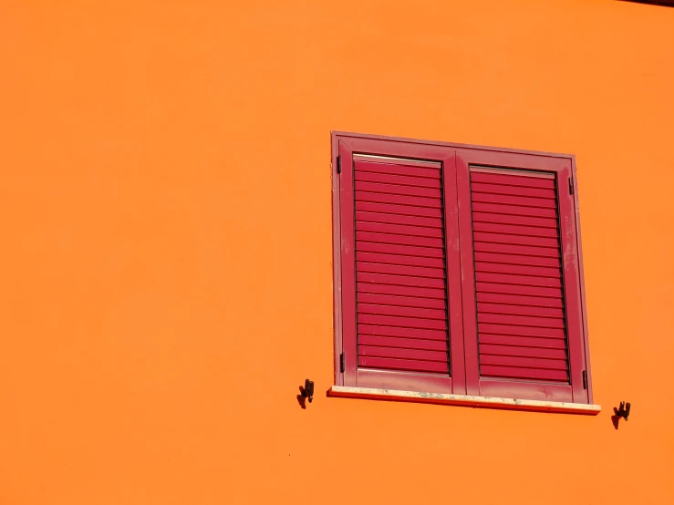 the side of an orange building with a window on top
