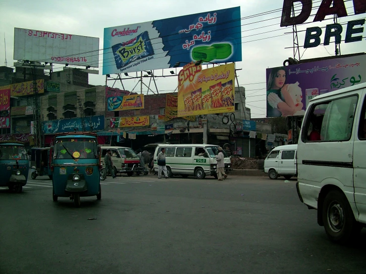 small car and a small vehicle on a city street with a billboard