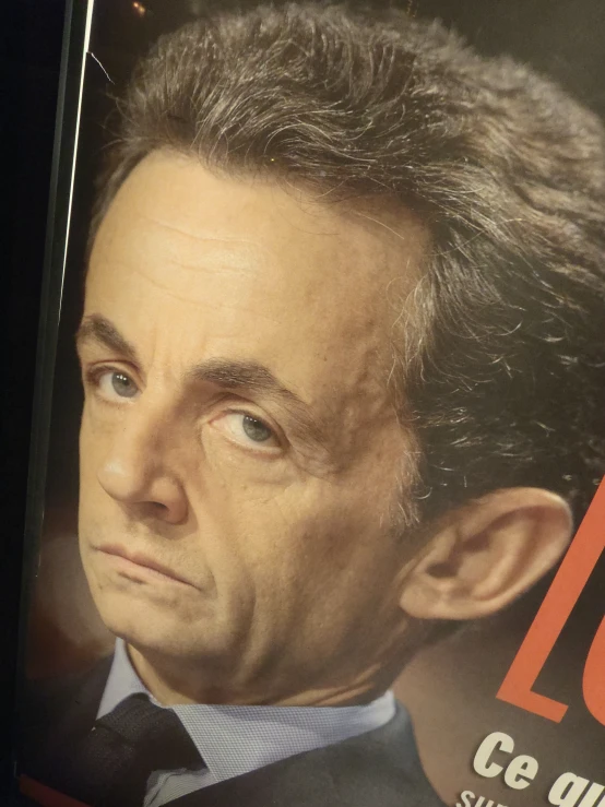 the head of an elderly man looking over his shoulder and wearing a suit