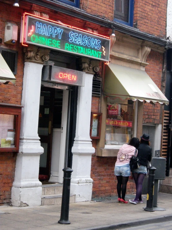 a couple of people standing outside of a restaurant