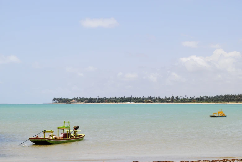 a boat floats on the water with a beach in the background