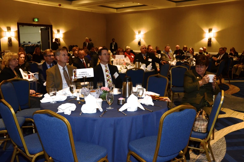 a group of people sitting at tables talking in a conference room