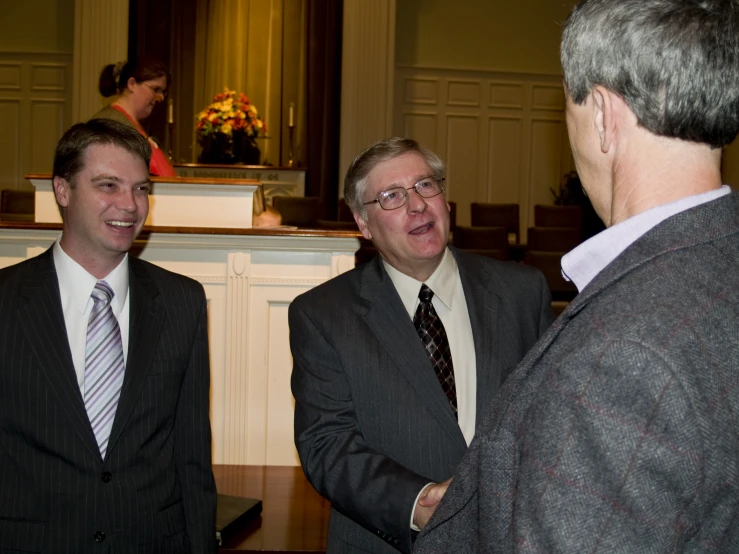 three businessmen in suits talking to each other