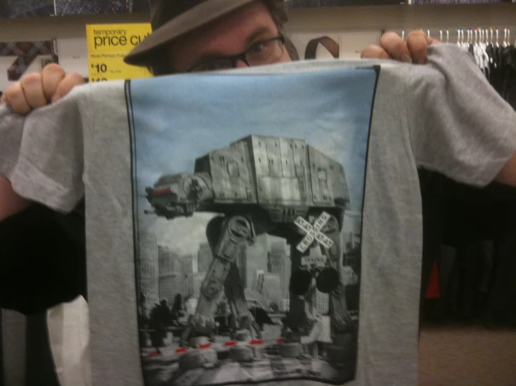 a man in glasses holding up a shirt with the image of a millennium falcon