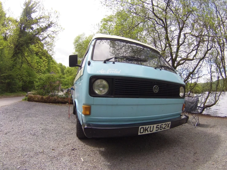 a small blue van parked on top of a gravel road