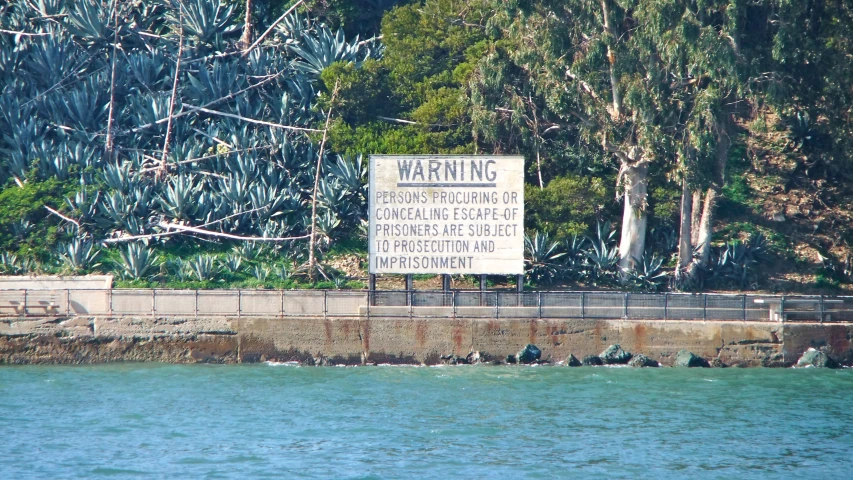 a large sign on the side of the road on the edge of a body of water