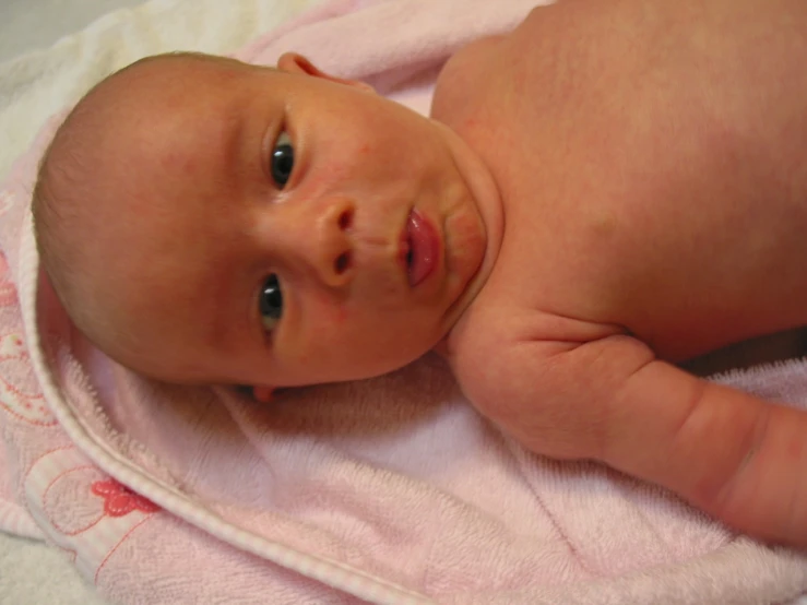 there is a baby with the eyes wide open on a towel