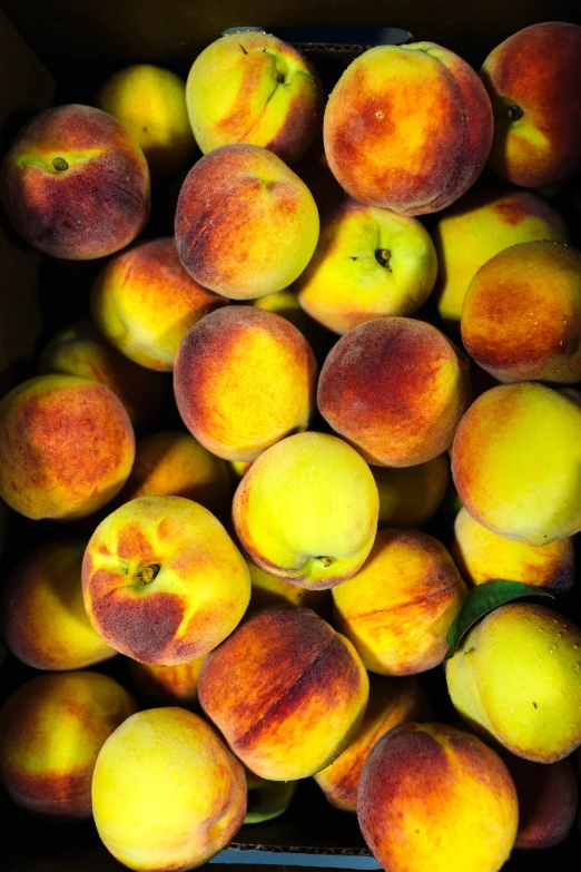 a bunch of peaches are piled together in a box