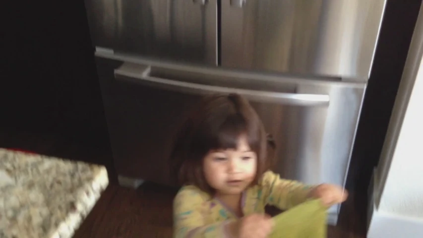 a  sitting on the floor next to a large metal refrigerator