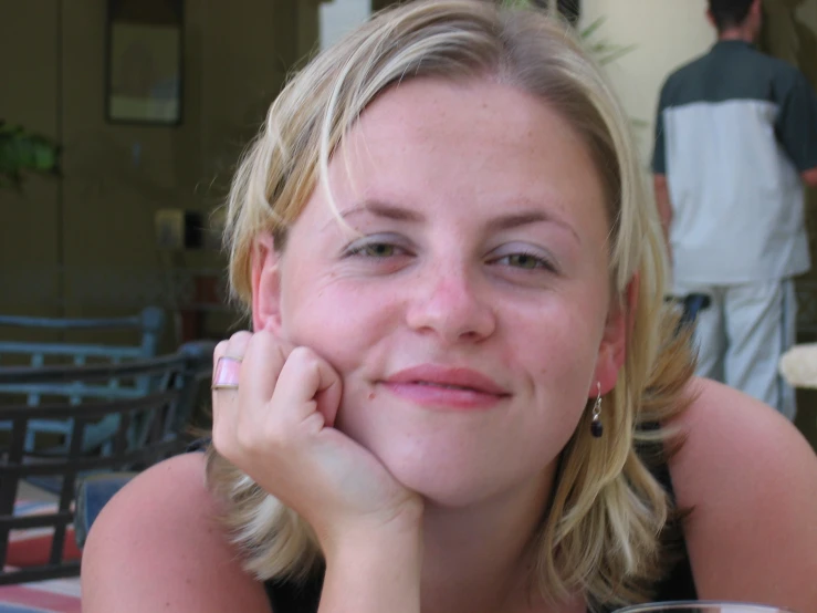 a smiling woman with her hand under her chin