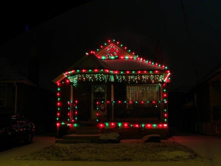a red and green house is decorated with christmas lights