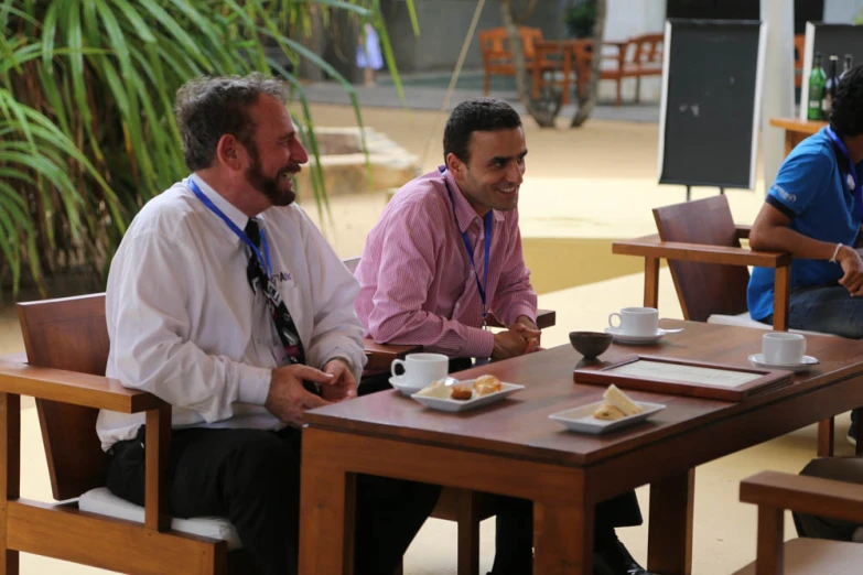 two men sit at a table with food and drinks