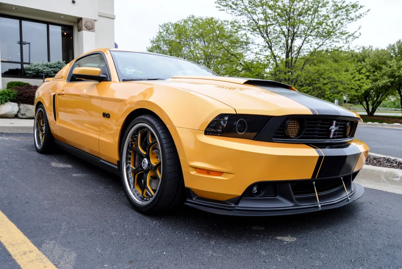 a yellow mustang is parked in front of a store