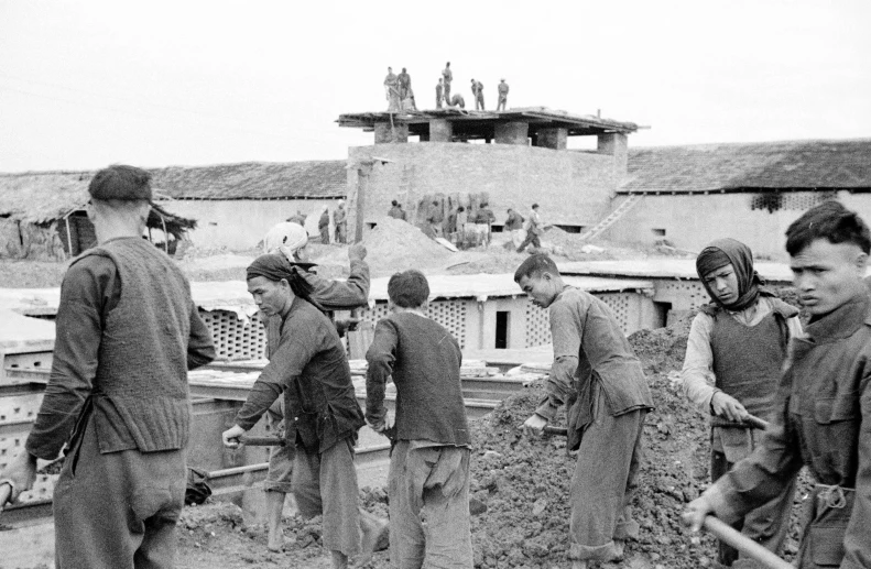 black and white pograph of boys wearing military uniforms in front of a destroyed building