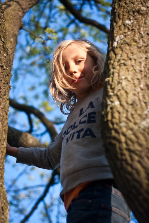 the little girl is climbing up a tree