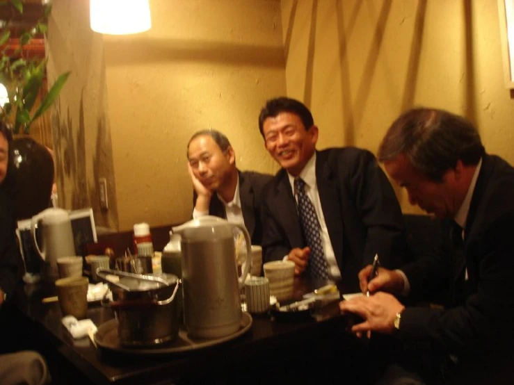 three men in suits are sitting around a table