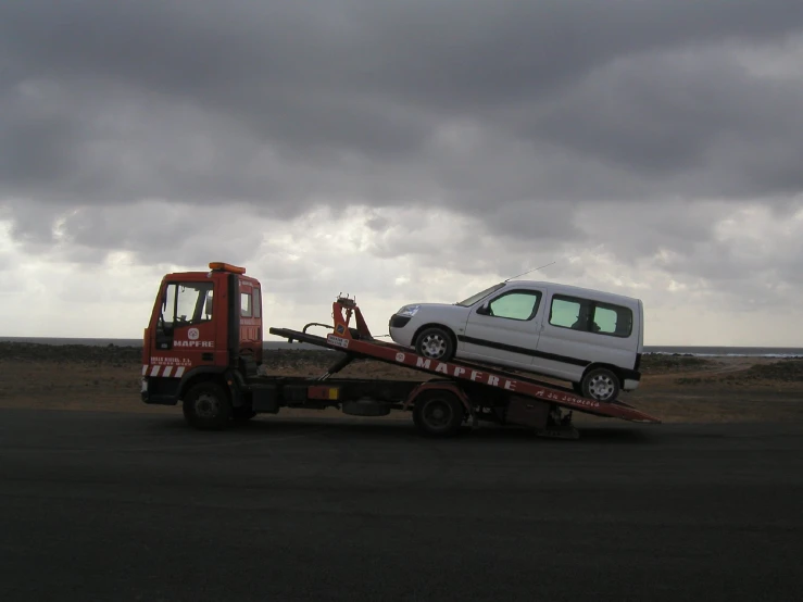 tow truck hauling a small white van in the middle of the desert