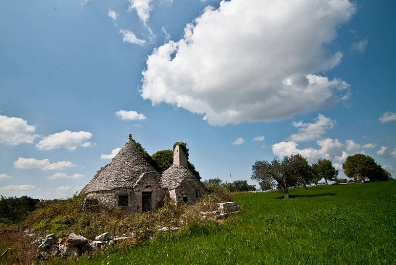 the old house is near a grassy field with rocks