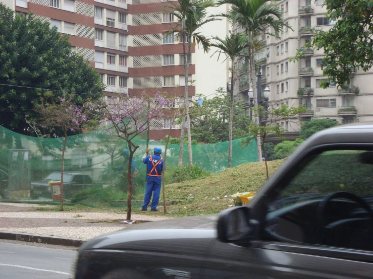 a man wearing an umbrella stands on the side of a road