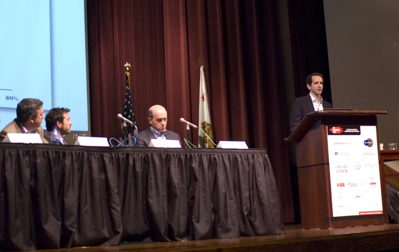 a panel of people sitting at a table on stage