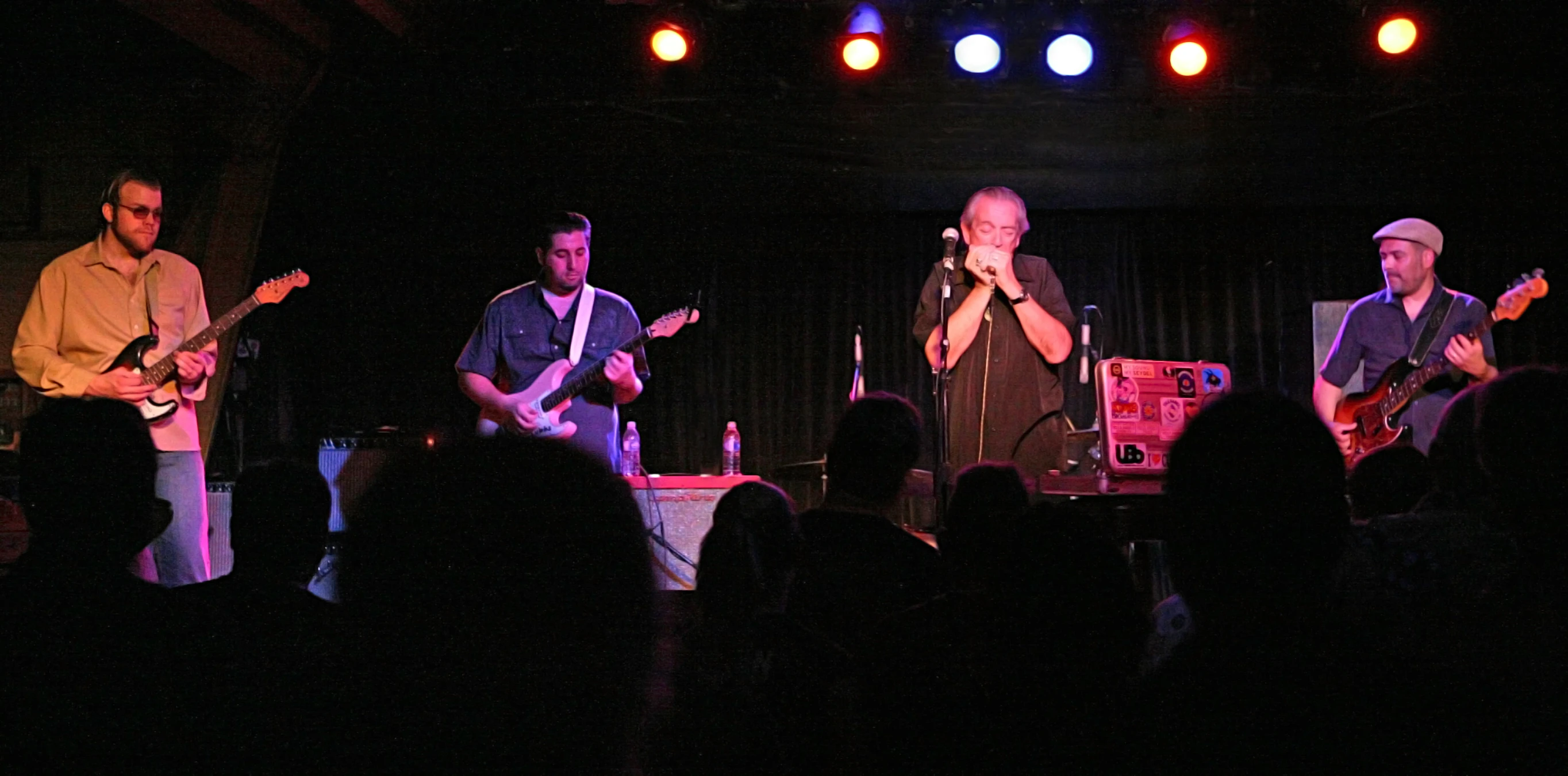 people in a darkened room with musical instruments