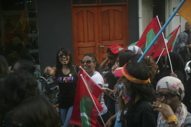 a group of people holding flags stand on the side of a building