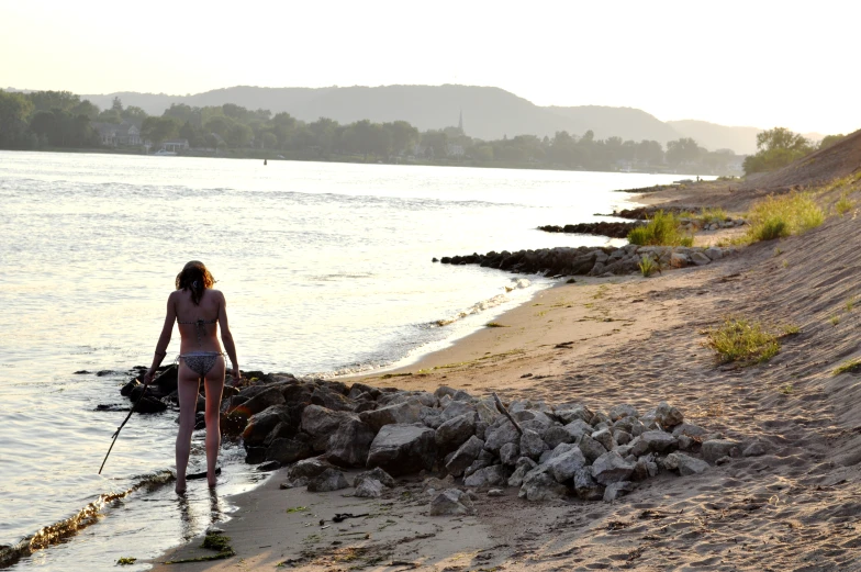 a woman in a bikini walks down the shore of the beach