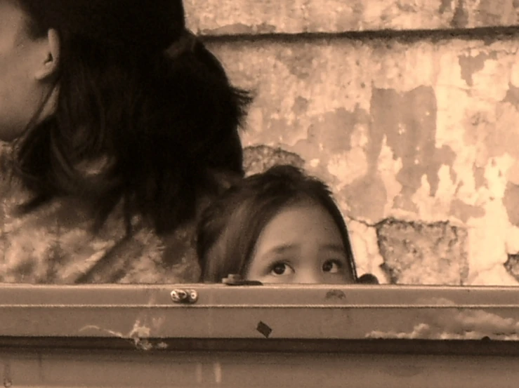 a child looks into the mirror while another girl watches