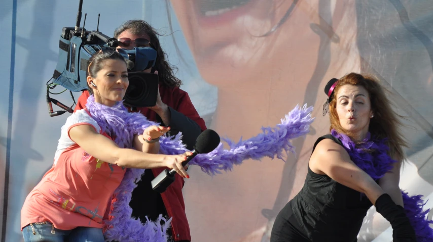 two women dressed in purple are singing with a microphone