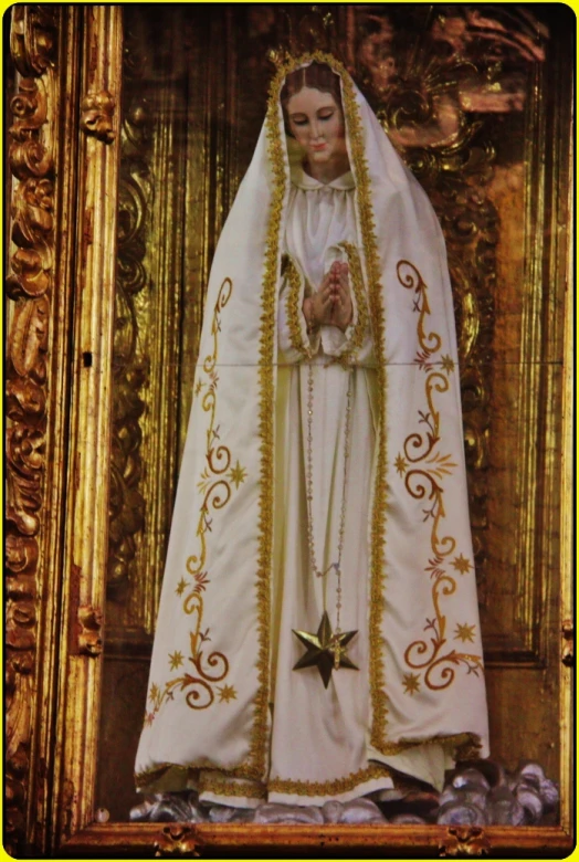 statue of mary wearing a white robe and gold star