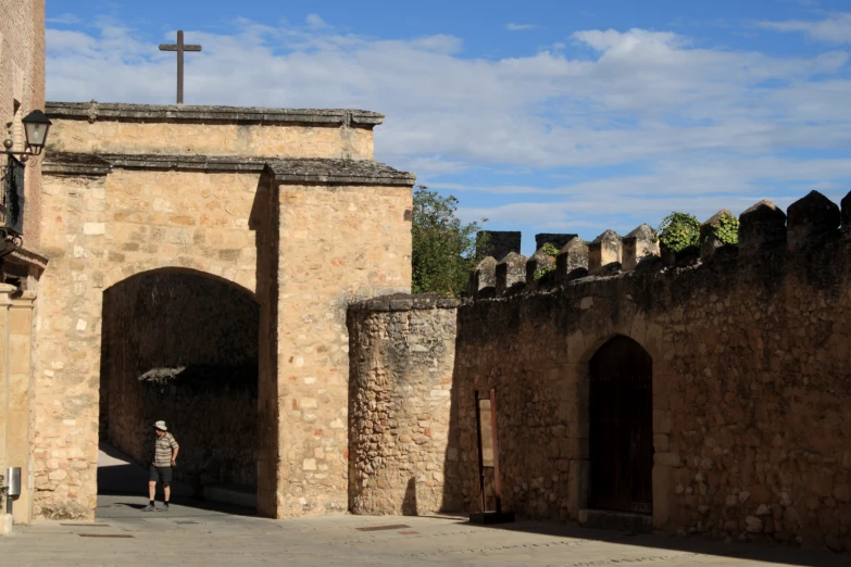 a man is standing under a building with a cross