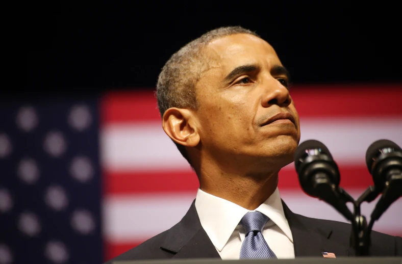 a man with a suit and tie speaks from a podium