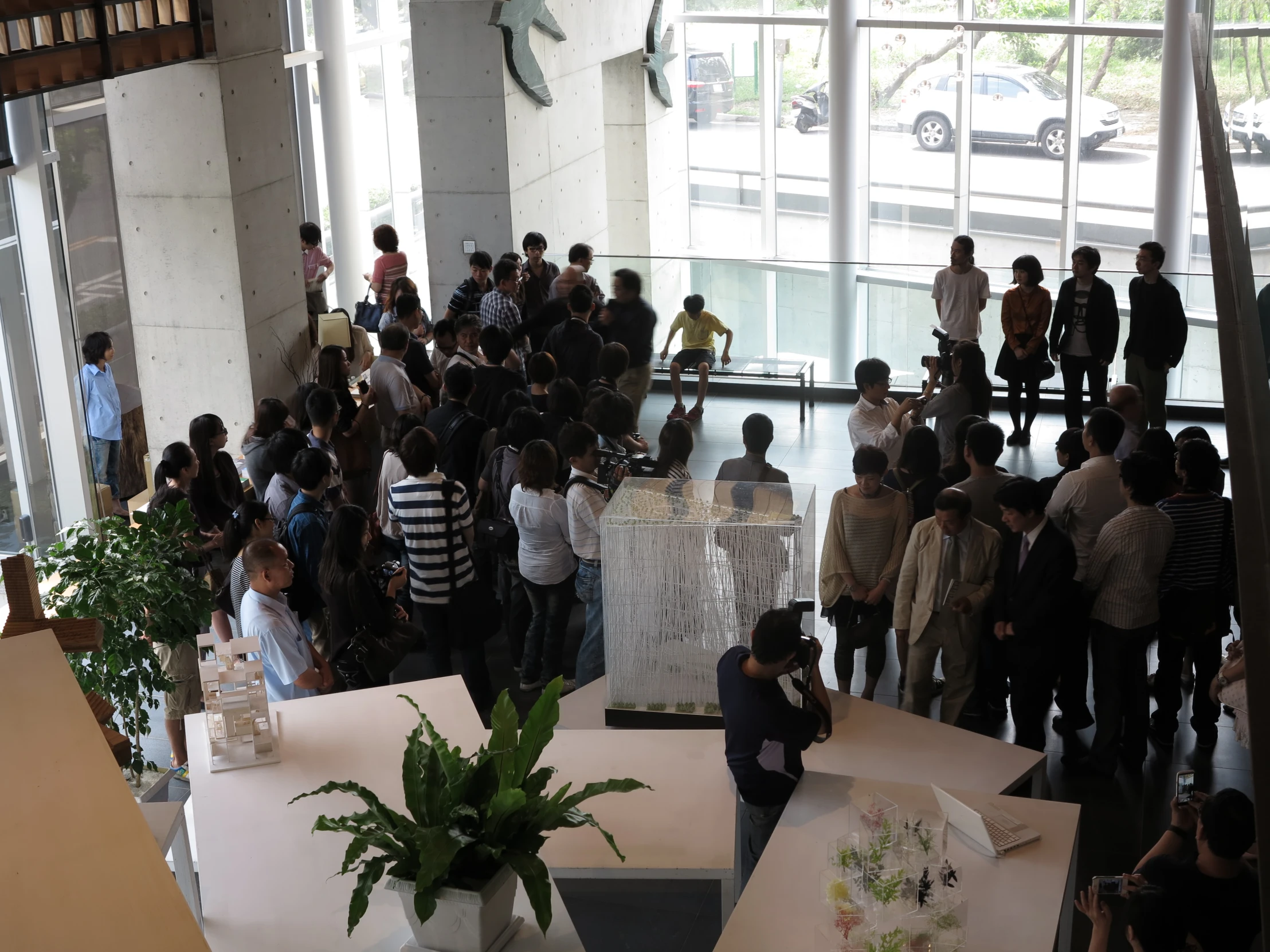 a large group of people are looking at various work in a room