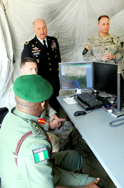some soldiers looking at soing on a computer screen