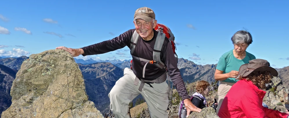 the man is reaching up to get off of a mountain